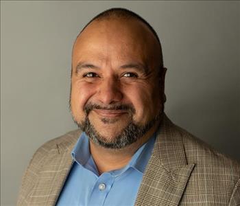 Man in brown coat and blue shirt smiling