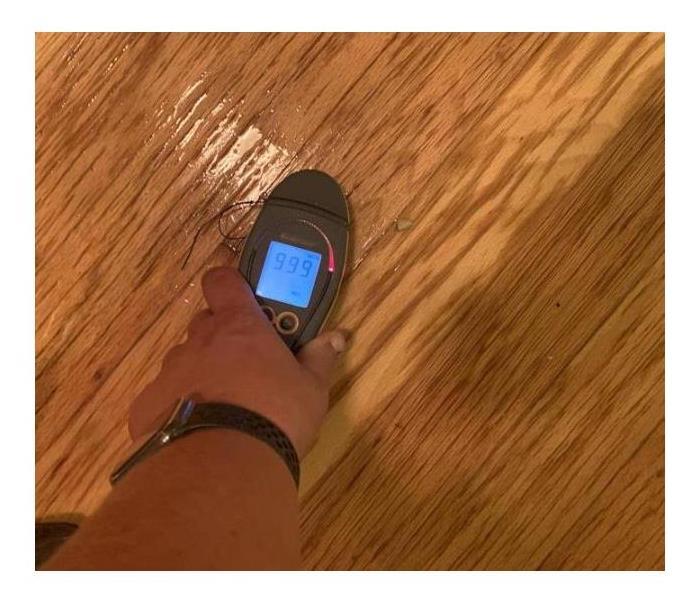 Meter showing wet readings on a wood floor