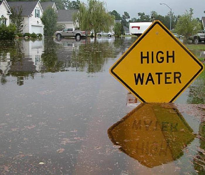 Flooded residential houses with street sign warning of High Waterof 