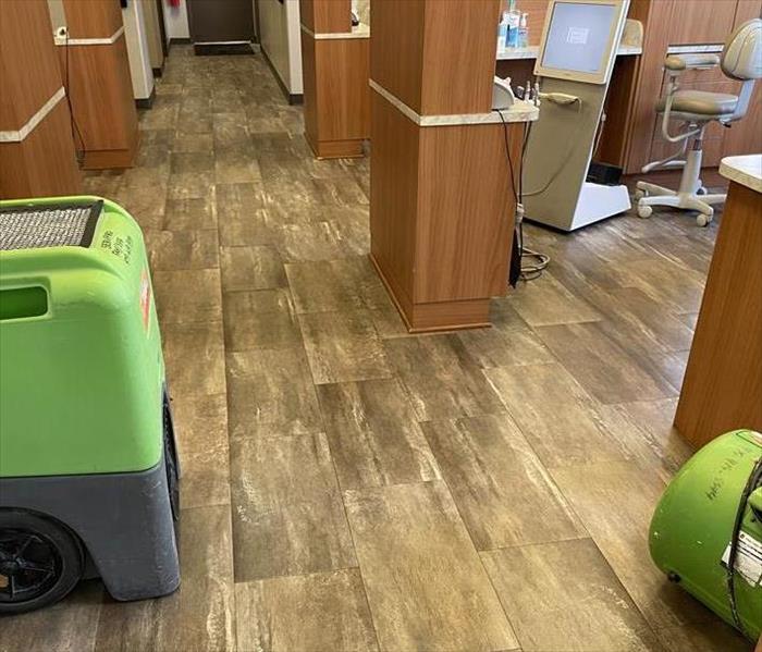Commercial grade air movers and dehumidifiers drying the cabinets and flooring of this dental office