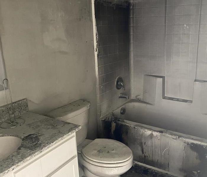 Bathroom vanity, toilet stool, and tub damaged by smoke and soot